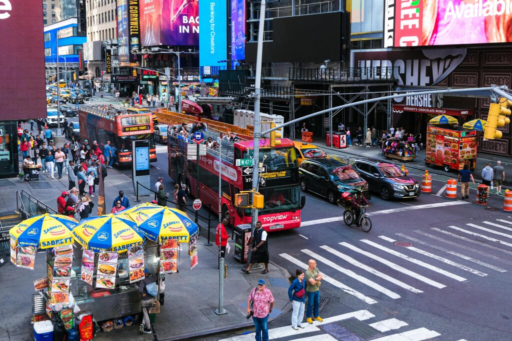 Dynamic street view of Times Square, NYC featuring tourists, buses, and vibrant billboards.